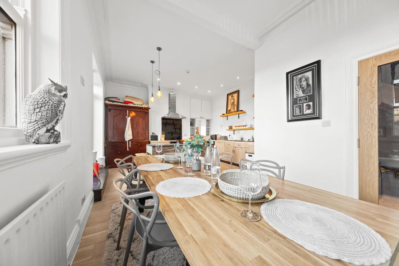 Un comedor moderno con una mesa de madera, sillas blancas y una escultura decorativa de un búho.