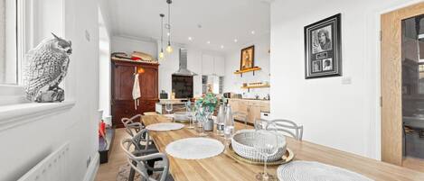 Un comedor moderno con una mesa de madera, sillas blancas y una escultura decorativa de un búho.