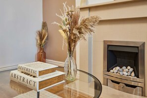 Une table en verre sur laquelle reposent deux livres intitulés « Esthétique » et « Abstrait », ainsi qu’un vase contenant des plantes séchées.