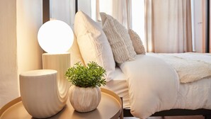 Une chambre à coucher avec un lit, une table de chevet avec une lampe et une plante en pot.