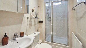 Une salle de bain avec un lavabo blanc, des toilettes et une douche à parois de verre.