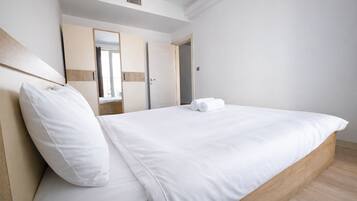 Una habitación de hotel con una cama grande, un cabecero de madera, un armario y un espejo.