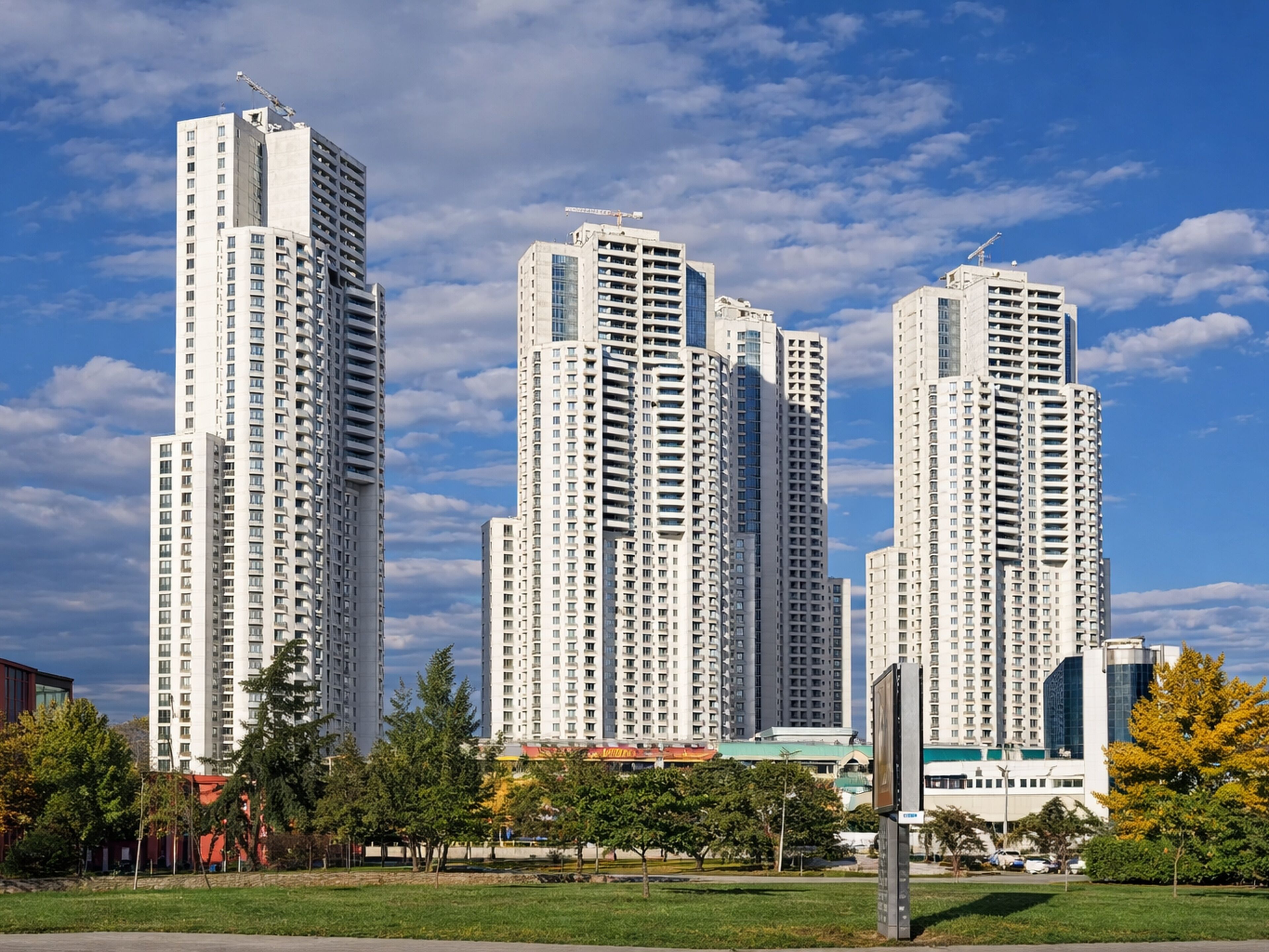 Un complesso residenziale di grattacieli con diversi edifici, immerso nel verde e sotto un cielo sereno.