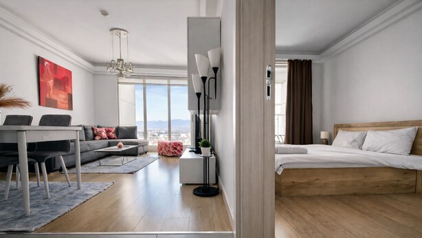 Una habitación de hotel moderna con una cama grande, un sofá, un comedor y vistas a la ciudad.