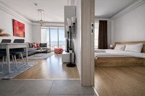 Et moderne hotelværelse med en stor seng, en sofa, et spiseområde og udsigt over byen.