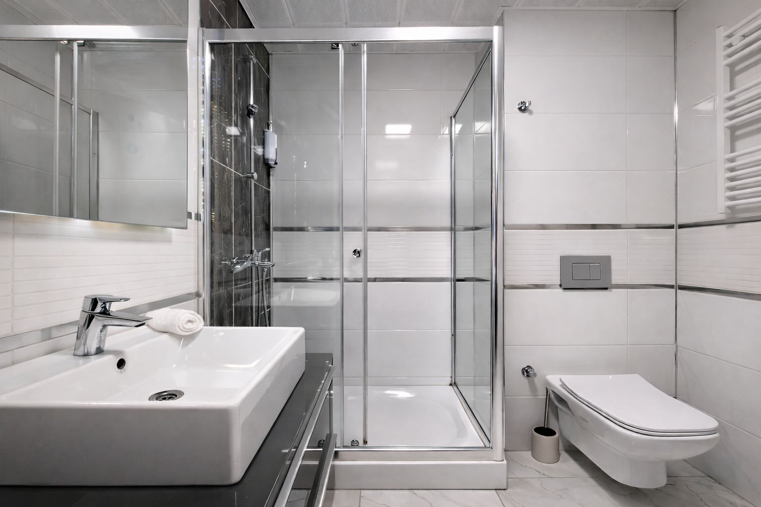 A modern bathroom with a glass-enclosed shower, a white sink, and a toilet.