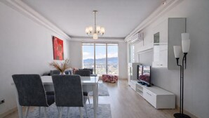 Una sala de estar moderna con comedor, ventanas amplias y vista a la ciudad.