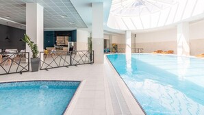 Una piscina interior con un diseño moderno, que cuenta con una piscina central grande y una piscina más pequeña contigua.