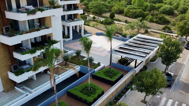 A multi-story residential building with balconies, a covered outdoor seating area, and a landscaped courtyard. - Loft 4 by Wonderful Italy (Olbia)