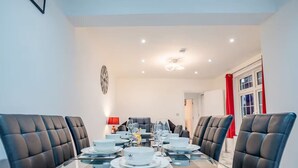 A dining area with a glass table, black leather chairs, white plates, and a red lamp. - Host Stay Broadland House (Southampton)