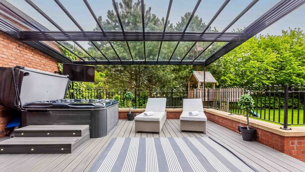 A covered outdoor deck with a hot tub, lounge chairs, and a striped rug. - Host Stay The Grove (Hartlepool)