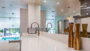 A modern kitchen with a large island, stainless steel appliances, and a view of an outdoor pool. - Host Stay The Grove (Hartlepool)