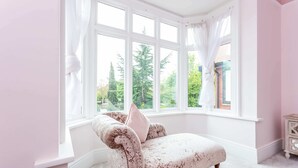 A room with a bay window, a plush armchair, and a small wooden side table. - Host Stay The Grove (Hartlepool)