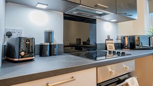 A modern kitchen with a built-in stove, a coffee maker, and a kettle.