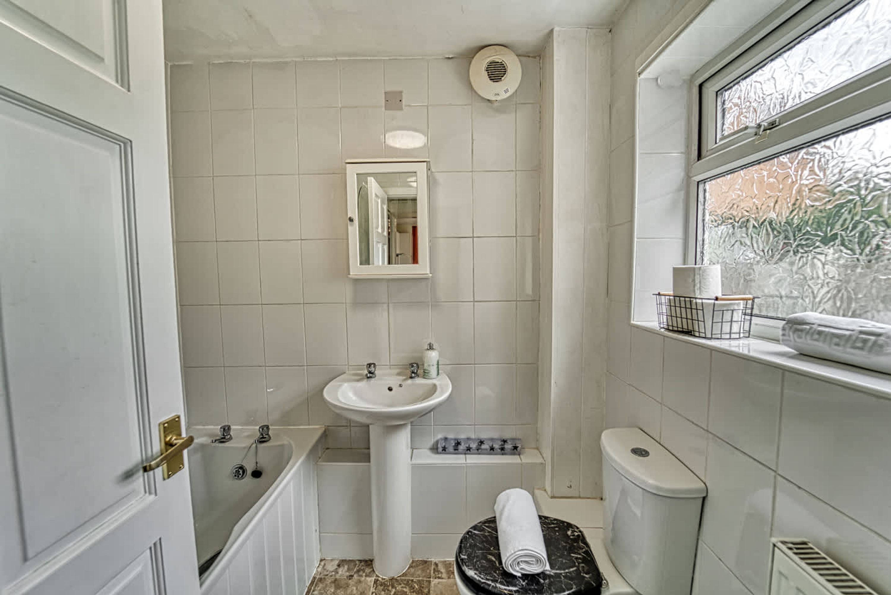 Ein Badezimmer mit Badewanne, Waschbecken, Toilette und einem Fenster mit Aussicht.