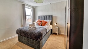 A bedroom with a large bed, a nightstand, a lamp, and a window with curtains. - Host Stay Southfield Residence (Worcester)