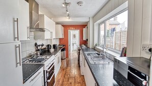 A modern kitchen with white cabinets, a black countertop, and a wooden floor. - Host Stay Southfield Residence (Worcester)