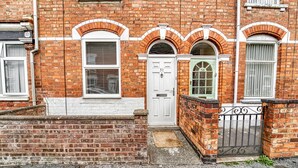 A red brick building with white-framed windows and doors, a small front porch, and a metal gate. - Host Stay Southfield Residence (Worcester)
