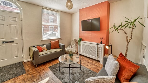 A living room with a sofa, armchair, coffee table, and a television mounted on the wall. - Host Stay Southfield Residence (Worcester)