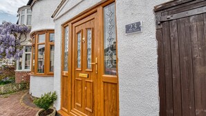 A house with a wooden front door, a number plaque, and a garden with purple flowers. - Host Stay Severn Swans House (Worcester)