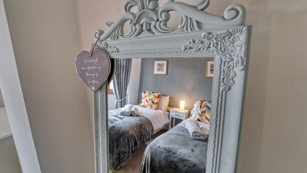 A bedroom with two beds, a mirror, and a heart-shaped decoration with a message. - Host Stay Severn Swans House (Worcester)