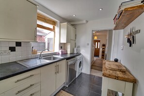 A compact kitchen with a washing machine, a sink, and a countertop. - Host Stay Severn Swans House (Worcester)