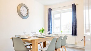 A dining area with a wooden table, grey chairs, and a wall clock. - Host Stay Chestnut Residence (Worcester)