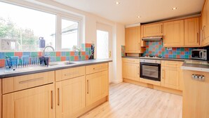 A modern kitchen with wooden cabinets, a stainless steel sink, and a colorful backsplash. - Host Stay Chestnut Residence (Worcester)