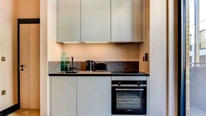 A modern kitchen with white cabinets, a built-in oven, and a countertop with a kettle and toaster.