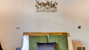 A bed with a wooden headboard, two green pillows, and a wall-mounted decorative piece.
