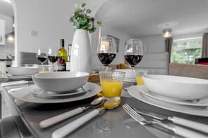 Una cucina moderna con elettrodomestici bianchi, un tavolo da pranzo apparecchiato con piatti, ciotole e bicchieri di succo d'arancia e vino rosso.
