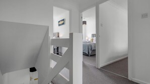 Un couloir avec un escalier menant à une chambre.
