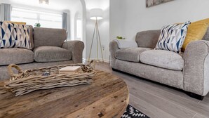 Un salon moderne avec deux canapés gris, une table basse en bois et un lampadaire.
