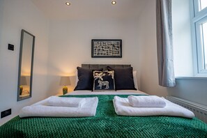 A neatly made bed with two white towels, a green blanket, and a framed picture of a tiger on the headboard. - Host Stay Carlisle Road House (Worcester)