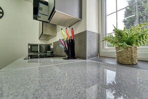 A kitchen with a granite countertop, a microwave, a toaster, and a knife block with colorful handles. - Host Stay Chester House Retreat (Kidderminster)