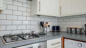 Eine Küche mit weißen Schränken, einem Gasherd und einer Kaffeemaschine.