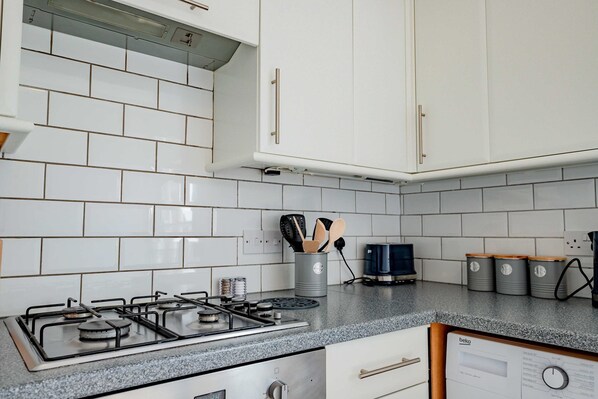 A kitchen with white cabinets, a gas stove, and a coffee maker.