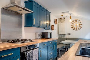 A modern kitchen with blue cabinets, a gas stove, a microwave, and a sink. - Host Stay Park Street Abode (Worcester)