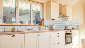 A kitchen with white cabinets, a window, a stove, and a sink. - Host Stay Upperley Barn (Bromyard)