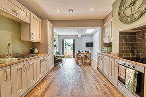 Eine moderne Küche mit Holzboden, eingebauten Schränken und einem Essbereich mit Tisch und Stühlen.