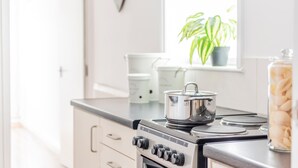 A kitchen with a stove, pots, and a window with plants. - Host Stay The Haven at Church Road (Great Yarmouth)