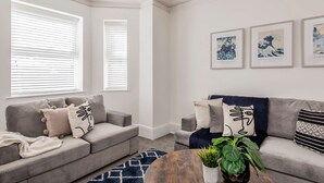 A living room with two grey sofas, a coffee table, and a potted plant. There are three framed artworks on the wall. - Host Stay The Haven at Church Road (Great Yarmouth)
