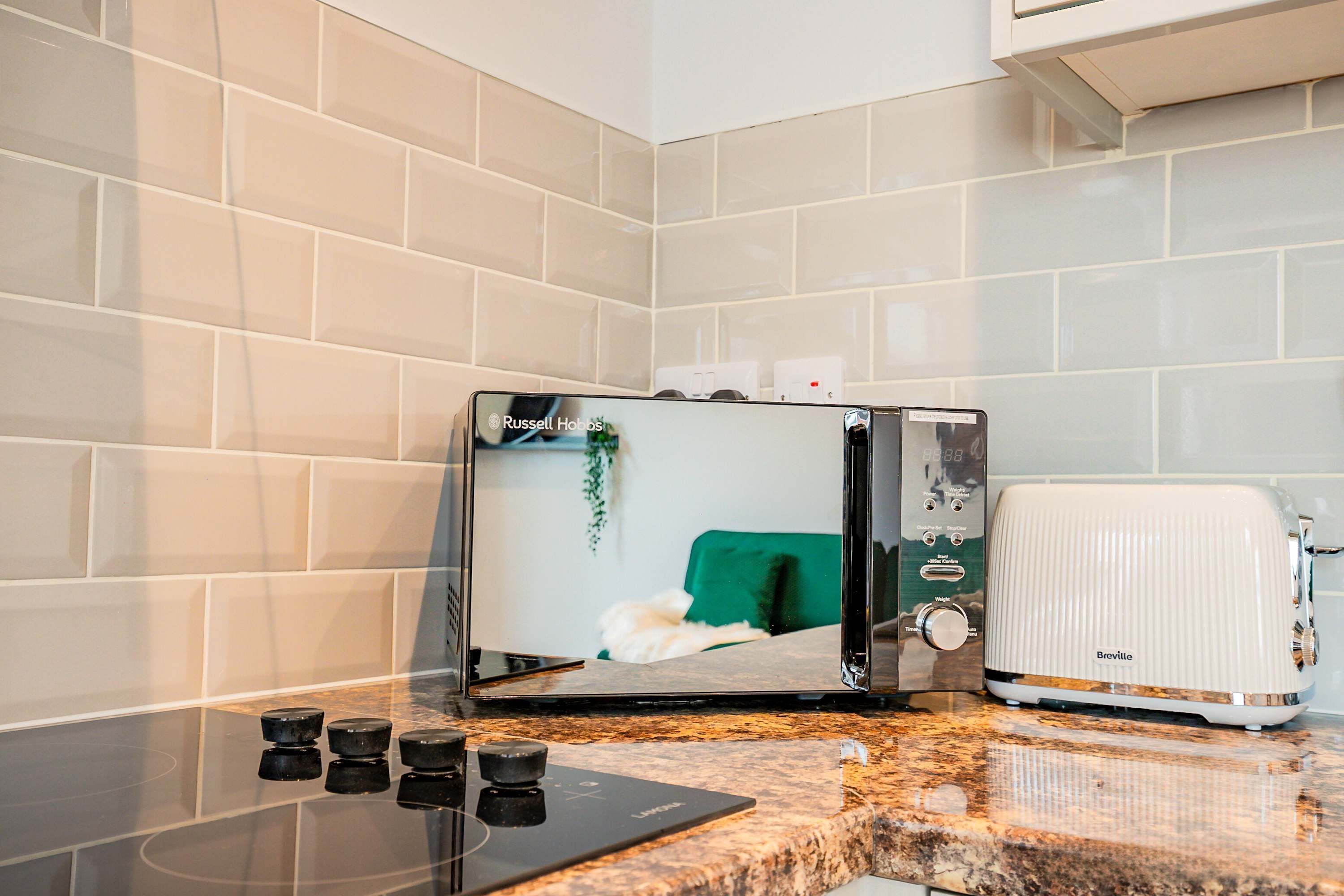 Una cocina de diseño moderno, con microondas integrado y un tostador blanco.
