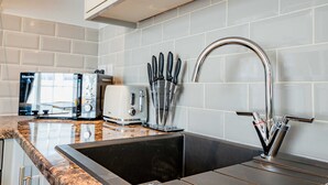 Eine Küche mit einer Edelstahlspüle, einem Toaster und einem Messerblock.