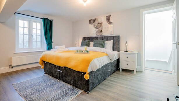 Ein Schlafzimmer mit Bett, Nachttisch und einem Fenster mit Vorhängen.