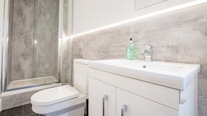 Ein Badezimmer mit einer Duschkabine, einer weißen Toilette und einem Waschbecken mit Seifenspender.