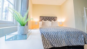 A modern bedroom with a large bed, a potted plant, and a bedside table. - Host Stay Shaw Street Suite (Worcester)