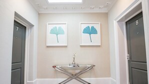 A hallway with two doors, numbered 7 and 8, and a glass-top table with a vase in the center. - Host Stay Shaw Street Suite (Worcester)