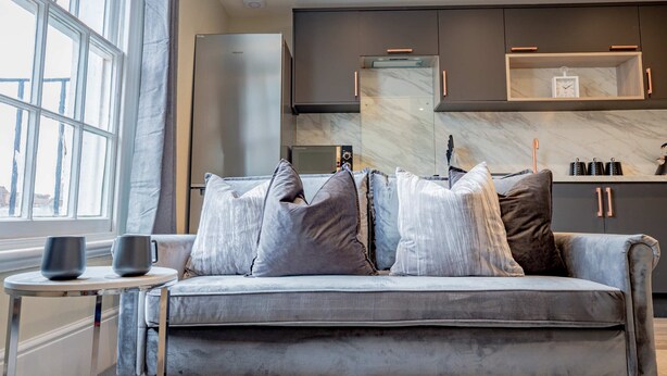 A modern kitchen with a grey sofa, two mugs, and a marble backsplash. - Host Stay Shaw Street Suite (Worcester)