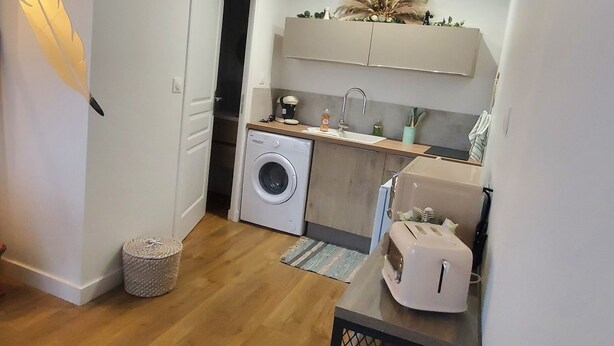 Une petite cuisine équipée d’un lave-linge, d’un évier et d’un grille-pain.